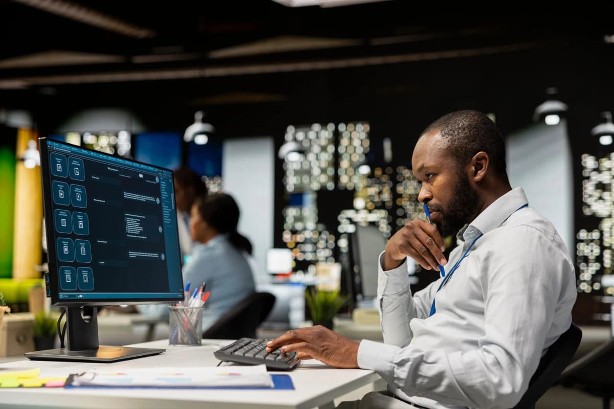 Collaborateur travaillant avec un assistant IA sur son poste dans un open space